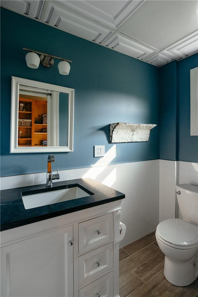 bathroom with vanity, hardwood / wood-style flooring, toilet, and tile walls