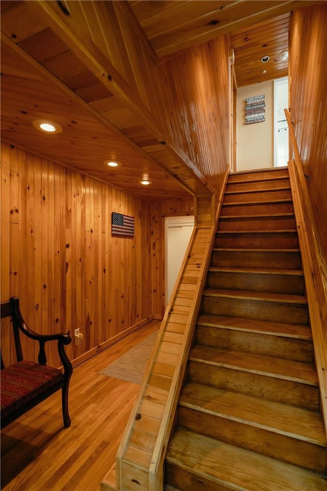 staircase featuring hardwood / wood-style floors, wooden ceiling, and wooden walls