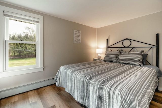 bedroom featuring hardwood / wood-style floors and a baseboard heating unit