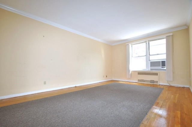 empty room featuring cooling unit, wood-type flooring, radiator heating unit, and crown molding