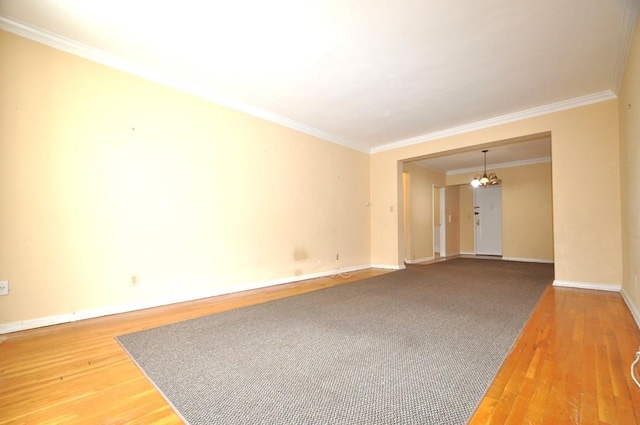 spare room featuring hardwood / wood-style floors, a chandelier, and ornamental molding