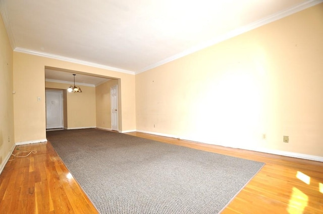 empty room featuring hardwood / wood-style floors, ornamental molding, and a notable chandelier