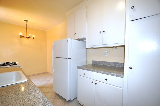 kitchen featuring light tile patterned floors, decorative light fixtures, white fridge, white cabinetry, and a chandelier