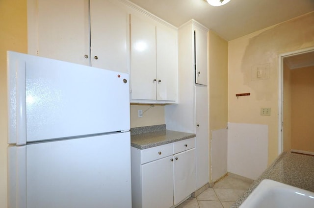 kitchen featuring white cabinets, white refrigerator, and light tile patterned flooring