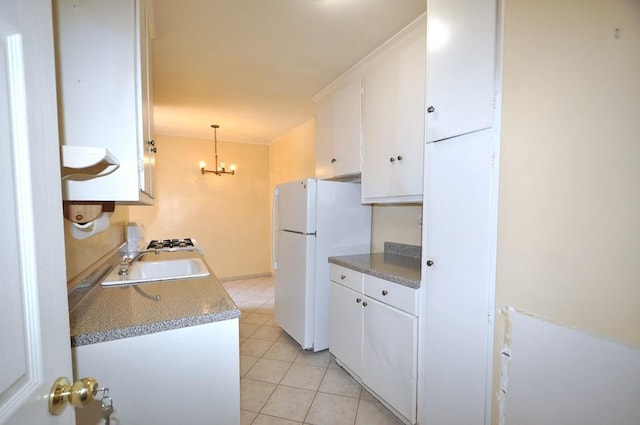 kitchen with pendant lighting, white refrigerator, sink, a notable chandelier, and white cabinetry