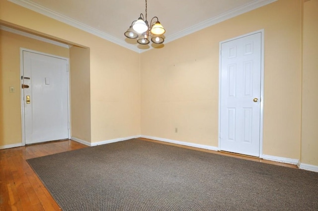 spare room with a chandelier, wood-type flooring, and crown molding