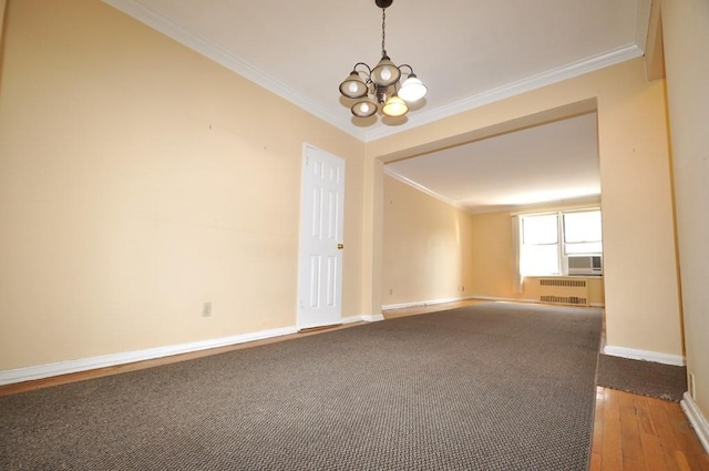 empty room with hardwood / wood-style floors, ornamental molding, radiator, and a chandelier