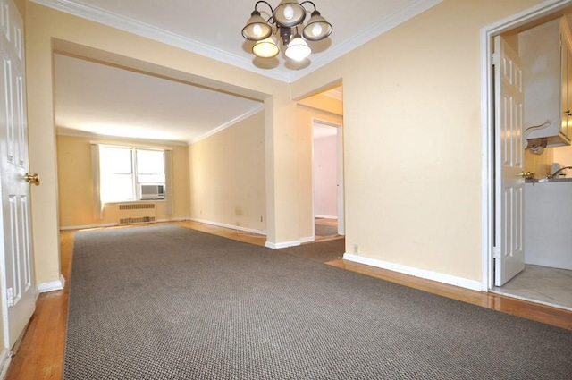 unfurnished room featuring wood-type flooring, radiator heating unit, crown molding, and a notable chandelier