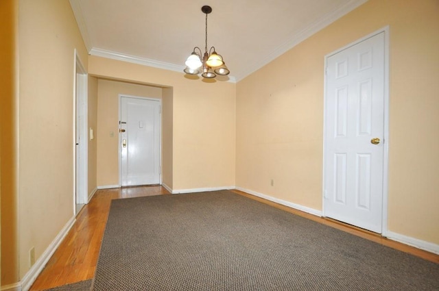 empty room featuring hardwood / wood-style flooring, a notable chandelier, and crown molding