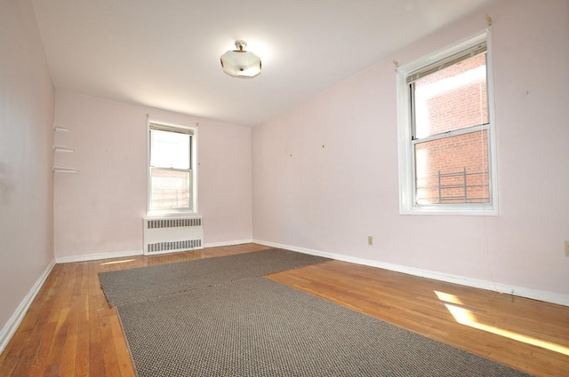 unfurnished room with radiator heating unit and hardwood / wood-style flooring