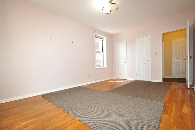 unfurnished bedroom with dark hardwood / wood-style floors and multiple closets