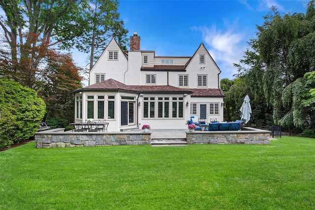 rear view of property with an outdoor living space, a patio, a sunroom, and a yard