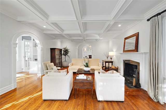 living room featuring beamed ceiling, wood-type flooring, coffered ceiling, and a high end fireplace