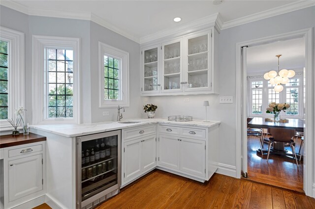 bar with wine cooler, sink, crown molding, light hardwood / wood-style flooring, and white cabinets