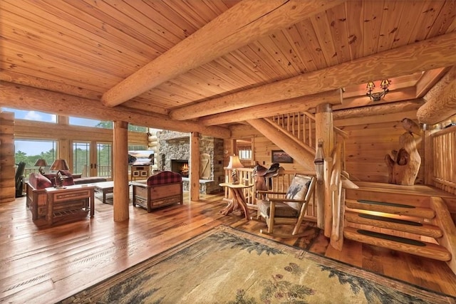 living room with beam ceiling, log walls, a stone fireplace, wood-type flooring, and wood ceiling