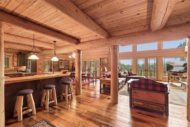 living room featuring hardwood / wood-style floors, wooden ceiling, french doors, log walls, and beam ceiling