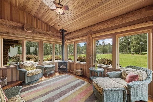 sunroom / solarium with a wood stove, ceiling fan, wooden ceiling, and lofted ceiling