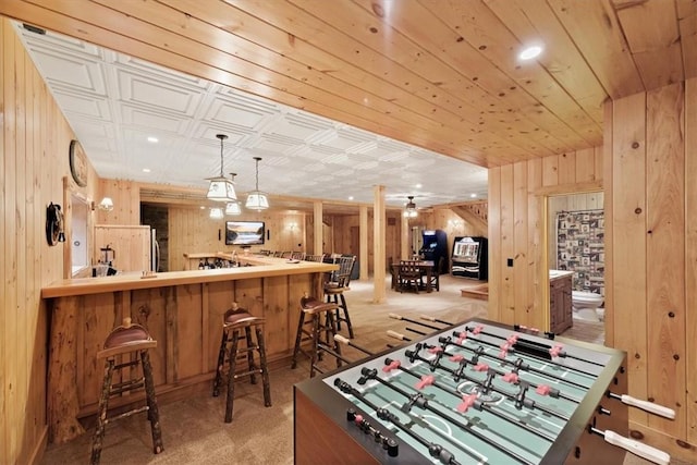 game room featuring wood walls, light colored carpet, and indoor bar