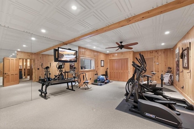 exercise room featuring ceiling fan, light colored carpet, and wood walls