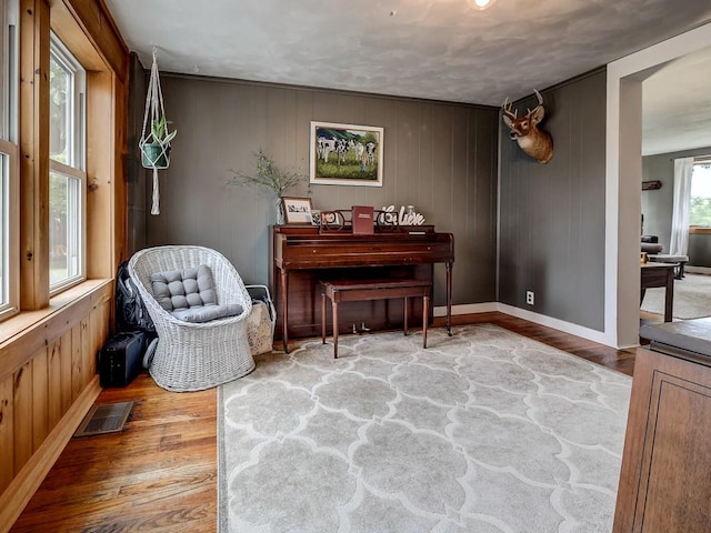 sitting room with hardwood / wood-style floors and wood walls