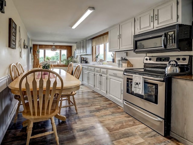 kitchen with electric stove, white cabinetry, and hardwood / wood-style flooring