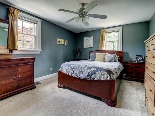 bedroom with ceiling fan, light colored carpet, and multiple windows