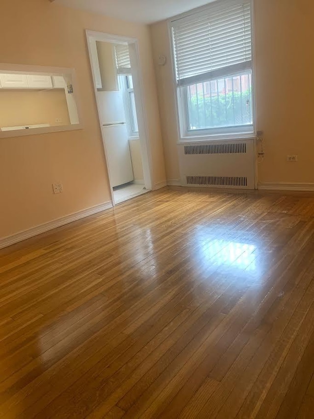 unfurnished room with radiator heating unit and wood-type flooring