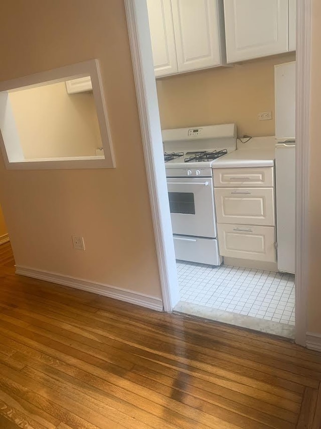 kitchen featuring white cabinetry, white appliances, and light hardwood / wood-style flooring