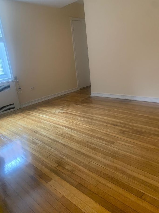 unfurnished room featuring radiator and light hardwood / wood-style flooring