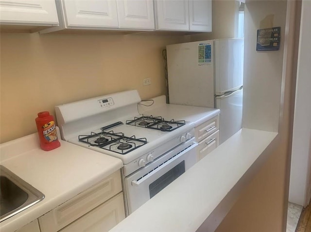 kitchen featuring white appliances, white cabinetry, and sink