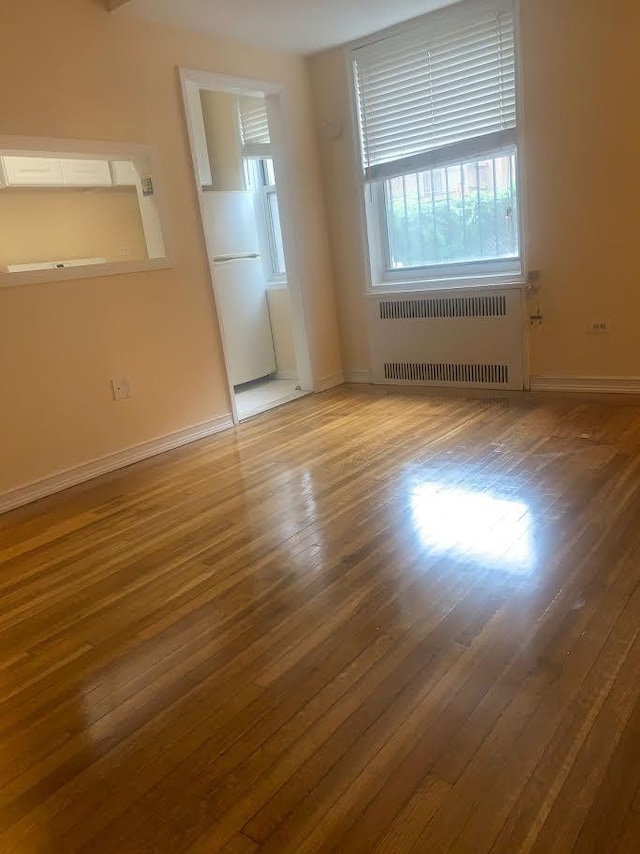 spare room with hardwood / wood-style flooring and radiator heating unit