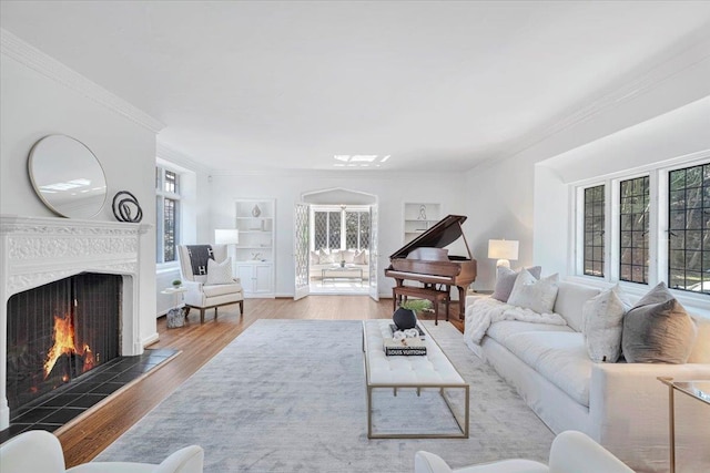 living area with crown molding, a fireplace, built in features, and wood finished floors