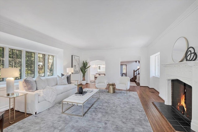 living area featuring a wealth of natural light, a fireplace, stairway, and wood finished floors