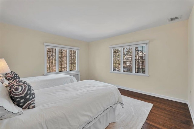 bedroom featuring wood finished floors, visible vents, baseboards, and multiple windows