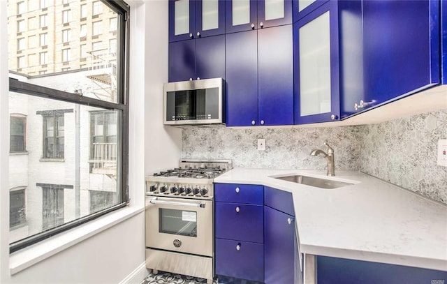 kitchen featuring appliances with stainless steel finishes, blue cabinets, plenty of natural light, and sink