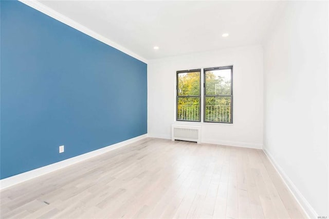 unfurnished room featuring light hardwood / wood-style flooring, radiator, and crown molding