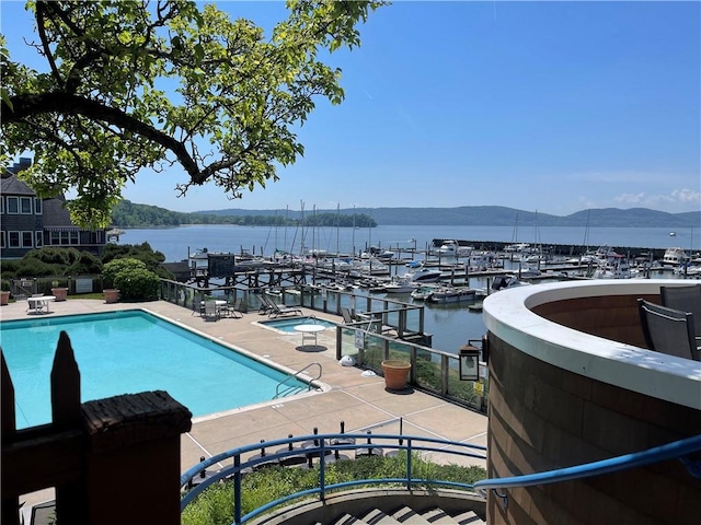 view of pool with a water and mountain view and a community hot tub