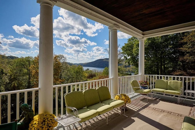 balcony with an outdoor living space and a water view