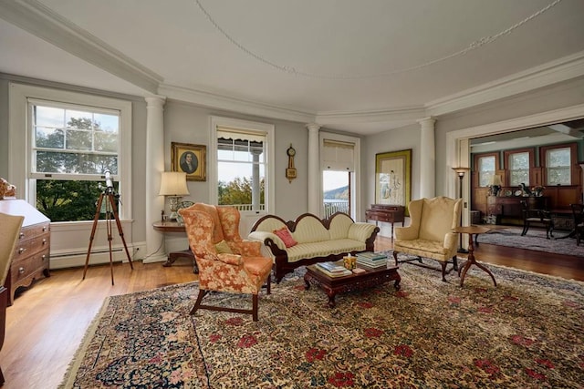 interior space with baseboard heating, a wealth of natural light, decorative columns, and hardwood / wood-style flooring