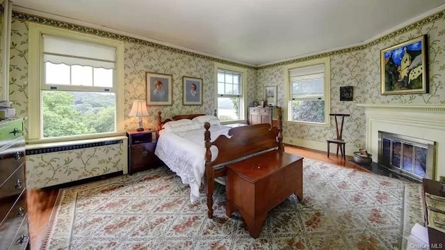 74 Tower Hill Loop, Tuxedo Park, NY 10987 - bedroom featuring wallpapered walls, wood finished floors, a glass covered fireplace, and ornamental molding