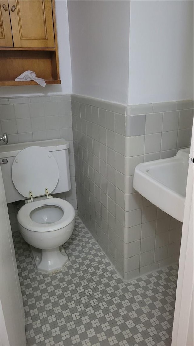 bathroom featuring sink, tile walls, and toilet