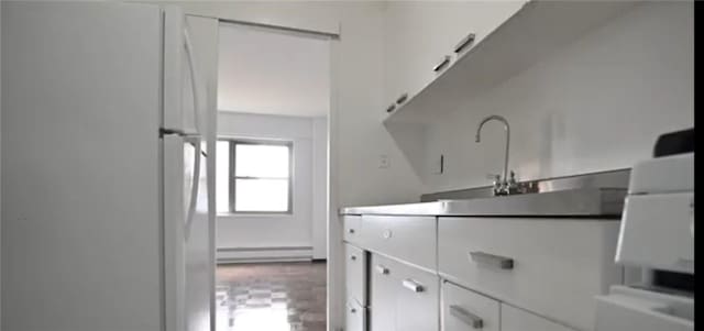 kitchen featuring baseboard heating, white cabinetry, sink, and white refrigerator