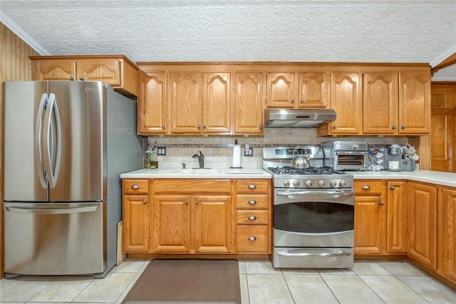 kitchen with sink, decorative backsplash, light tile patterned floors, a textured ceiling, and stainless steel appliances