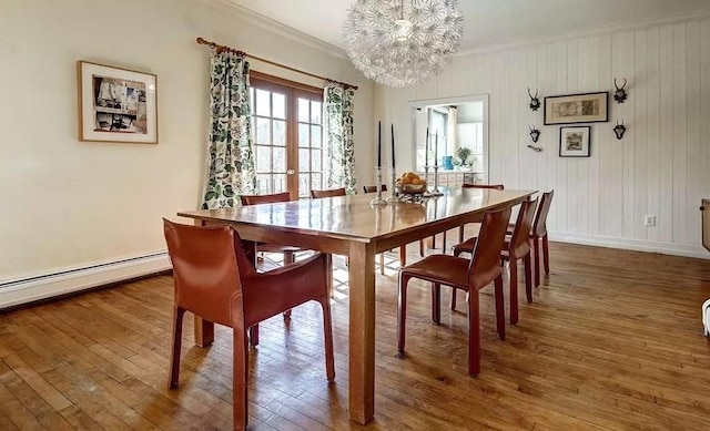 dining room featuring french doors, dark wood-type flooring, baseboard heating, a notable chandelier, and ornamental molding