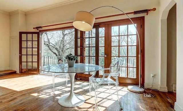 unfurnished dining area with crown molding, french doors, and wood-type flooring