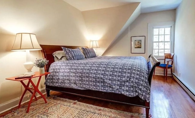 bedroom featuring lofted ceiling, wood-type flooring, and a baseboard radiator