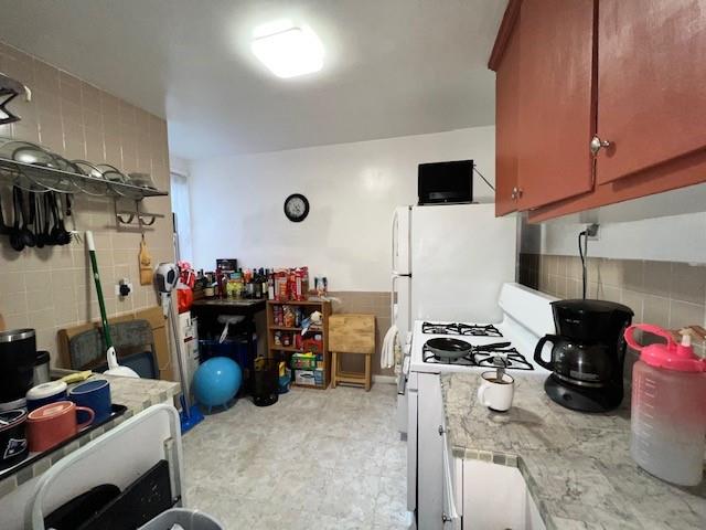 kitchen with white gas range oven and tile walls