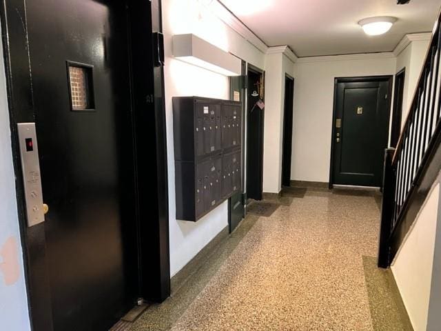 corridor featuring a mail area, crown molding, and elevator