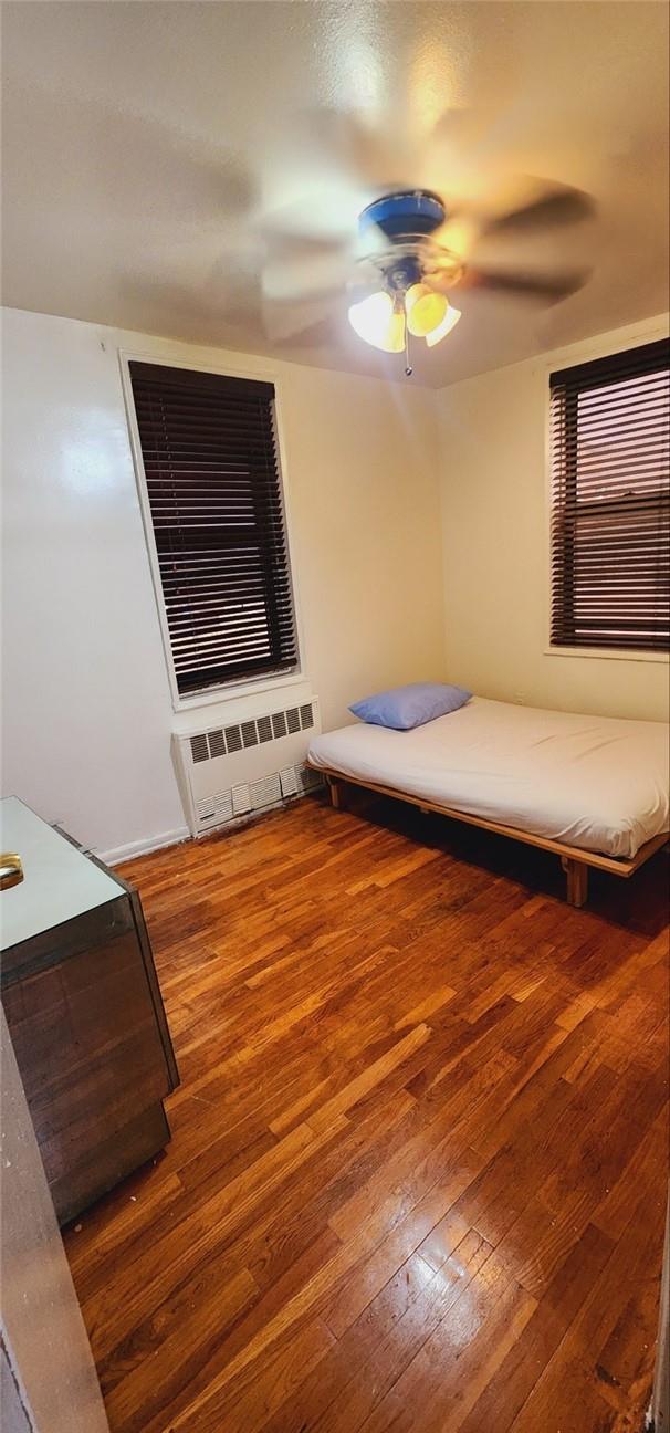 bedroom featuring ceiling fan, wood-type flooring, and radiator