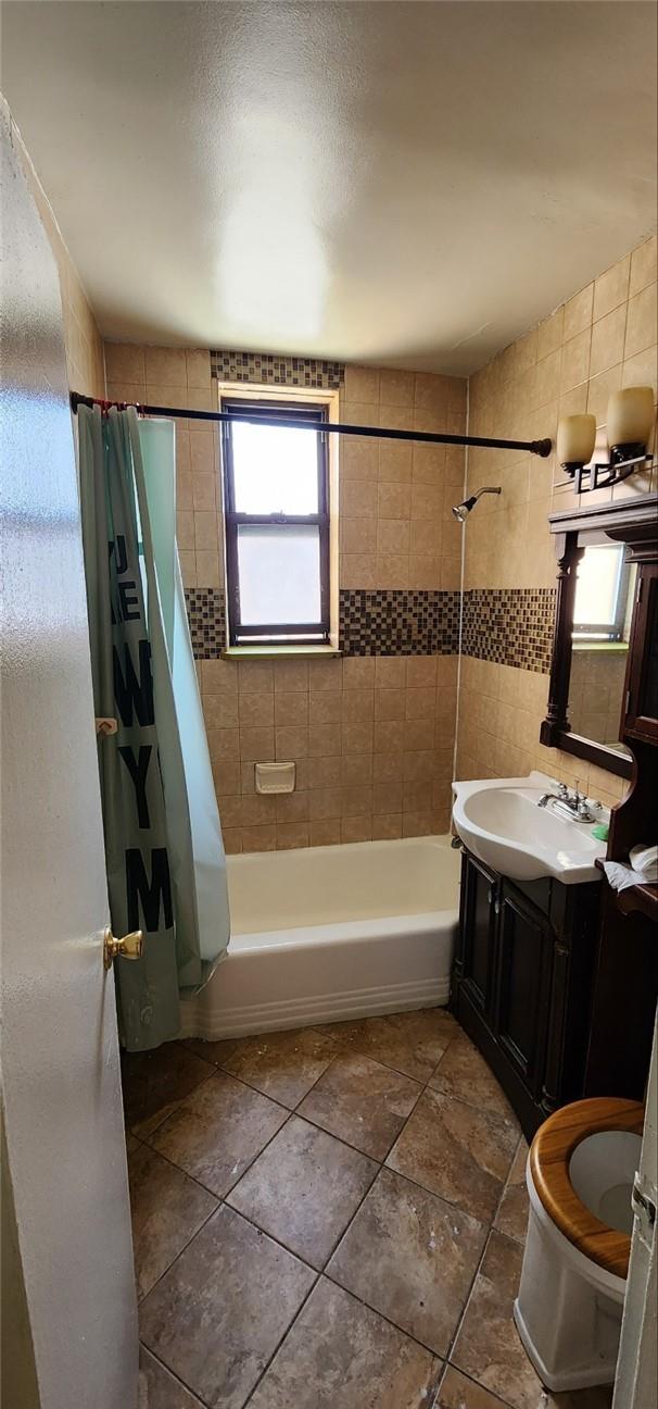 bathroom featuring vanity, shower / bathtub combination with curtain, and tile walls